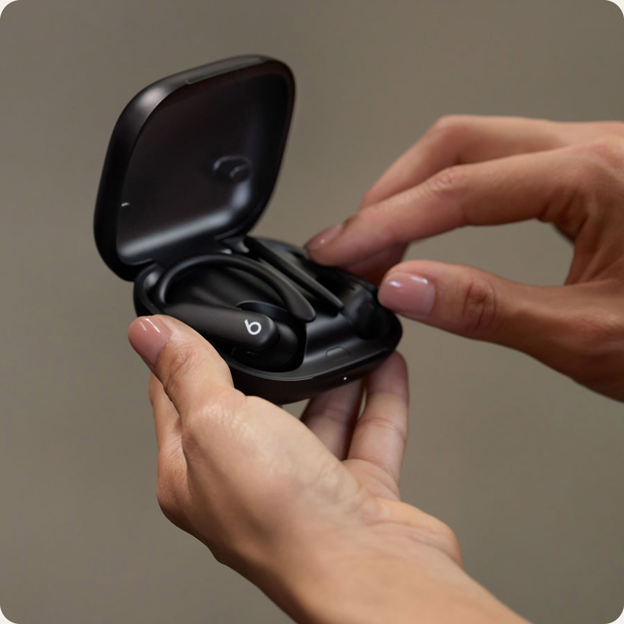 特写:一个人手持打开的充电盒,盒内装有 Powerbeats Pro 2 耳机