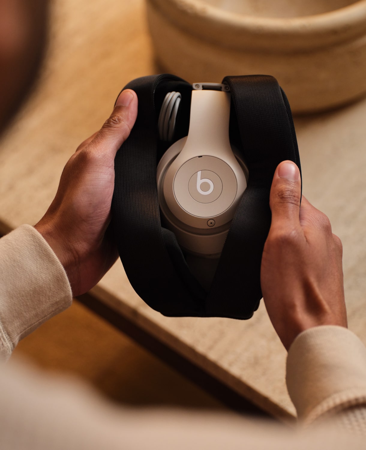 手持柔沙色 Beats Studio Pro 无线头戴式耳机的人